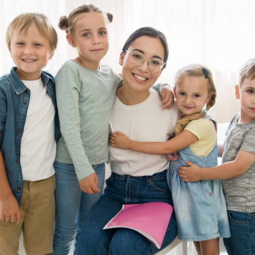 smiley-teacher-holding-her-students-scaled.jpg